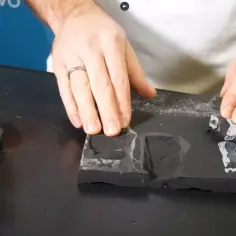 Dłoń układa fragmenty EPDM na styropianie, demonstrując klejenie.