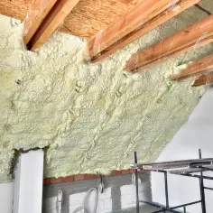 Ocieplenie dachu pianą PUR. Widoczne drewniane krokwie i izolacja z pianki.