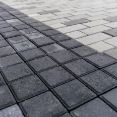 Szara i biała kostka brukowa ułożona w geometryczny wzór. Zastanawiasz się, ile kostki na m2?
