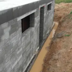 Budowa fundamentów z bloczków betonowych, widoczny wykop z wodą, kluczowy etap jak zrobić odwodnienie domu.