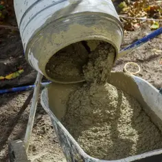 Mieszanie betonu w betoniarce, gotowego do rozsypania. Trudno określić ile piasku na m2, ale konsystencja wygląda na idealną do pracy.