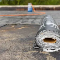 Rolka papy na dachu, przygotowana do smarowania na zimno. Cena robocizny za takie prace jest kluczowa.