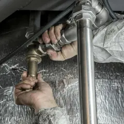 Ręce fachowca dokręcają złączki instalacji. Trwa ważny **test szczelności** systemu, by zapewnić jego bezpieczeństwo.